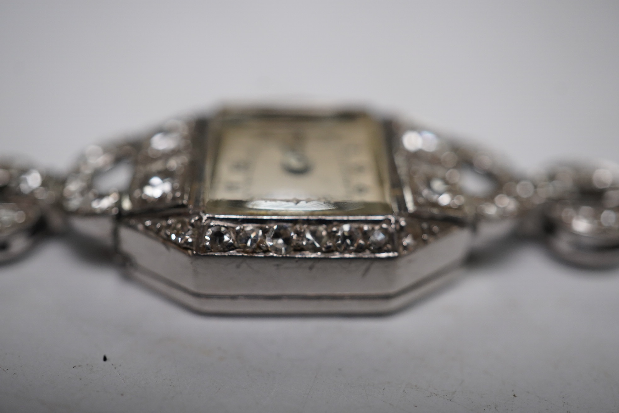 A lady's 1950's white metal and diamond cluster set manual wind cocktail watch, on a 9ct white gold bracelet, overall length 17.5cm, gross weight 17.1 grams. Condition - fair